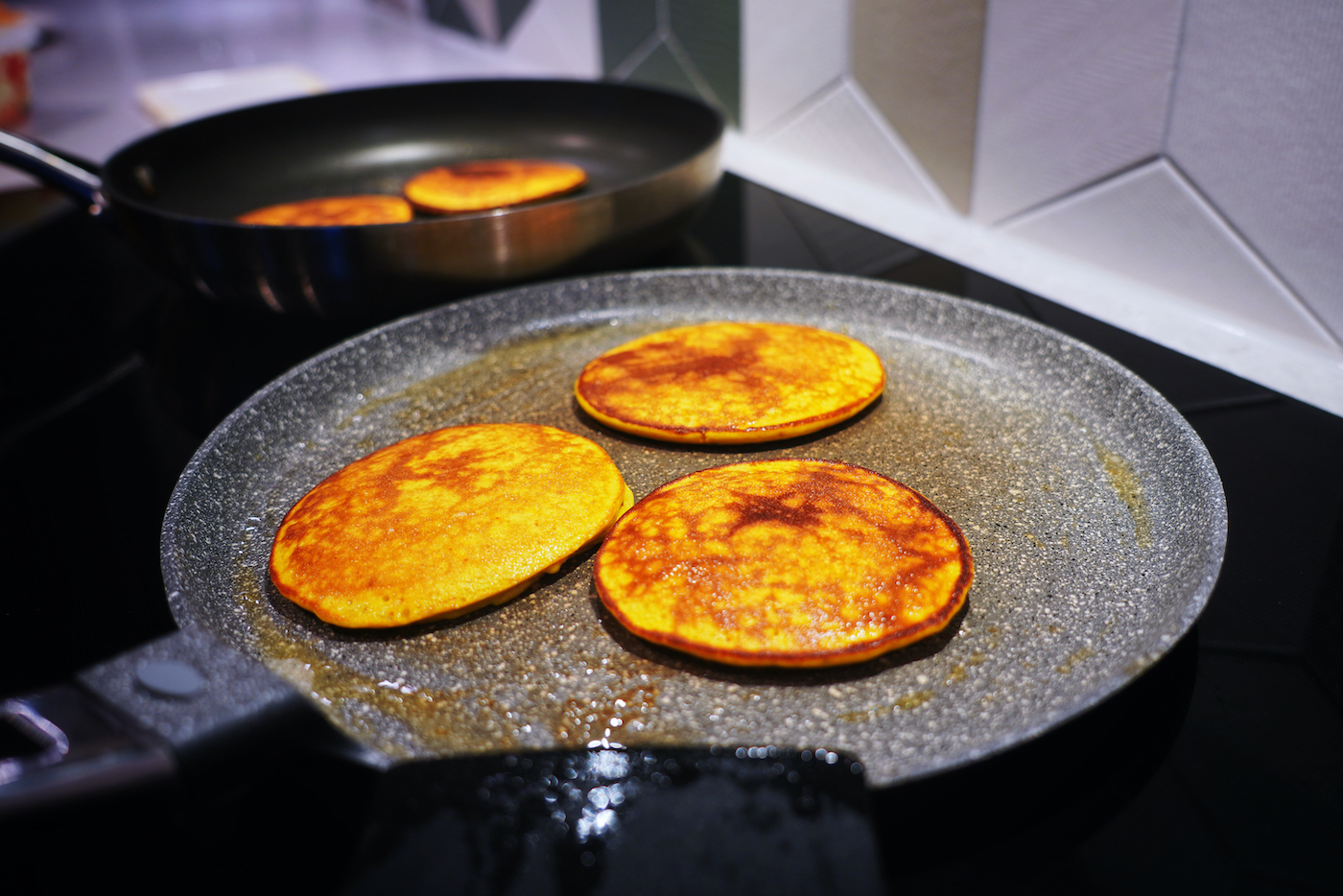 Banana and saffron pancakes in the pan fried on one side