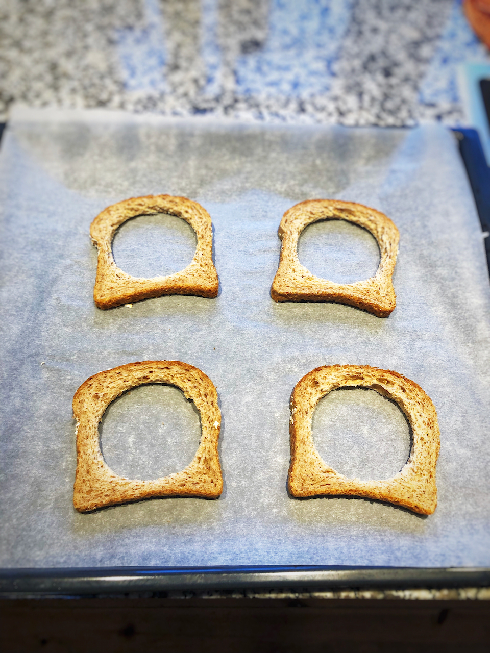 Take the 2 pieces of bread and make a round hole in the middle with a glass